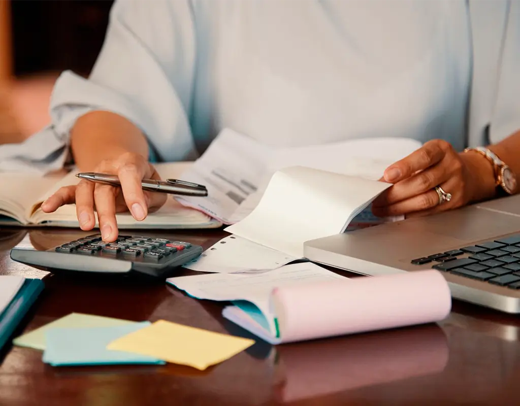 asesoría contable revisando facturas y cálculos financieros con calculadora y ordenador