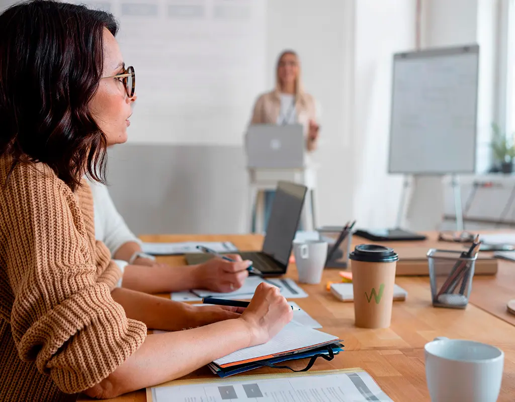 asesora laboral en reunión de trabajo tomando notas durante una presentación en oficina